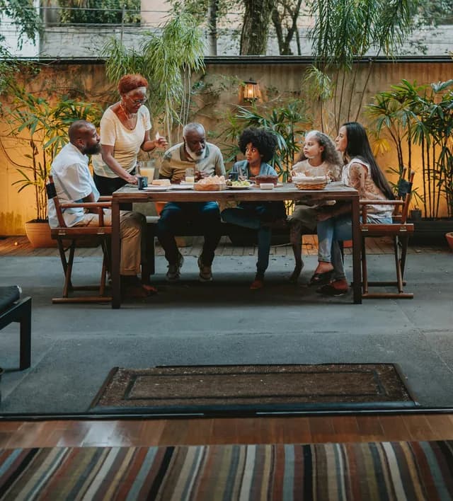 A family sharing a meal at a long table in a courtyard