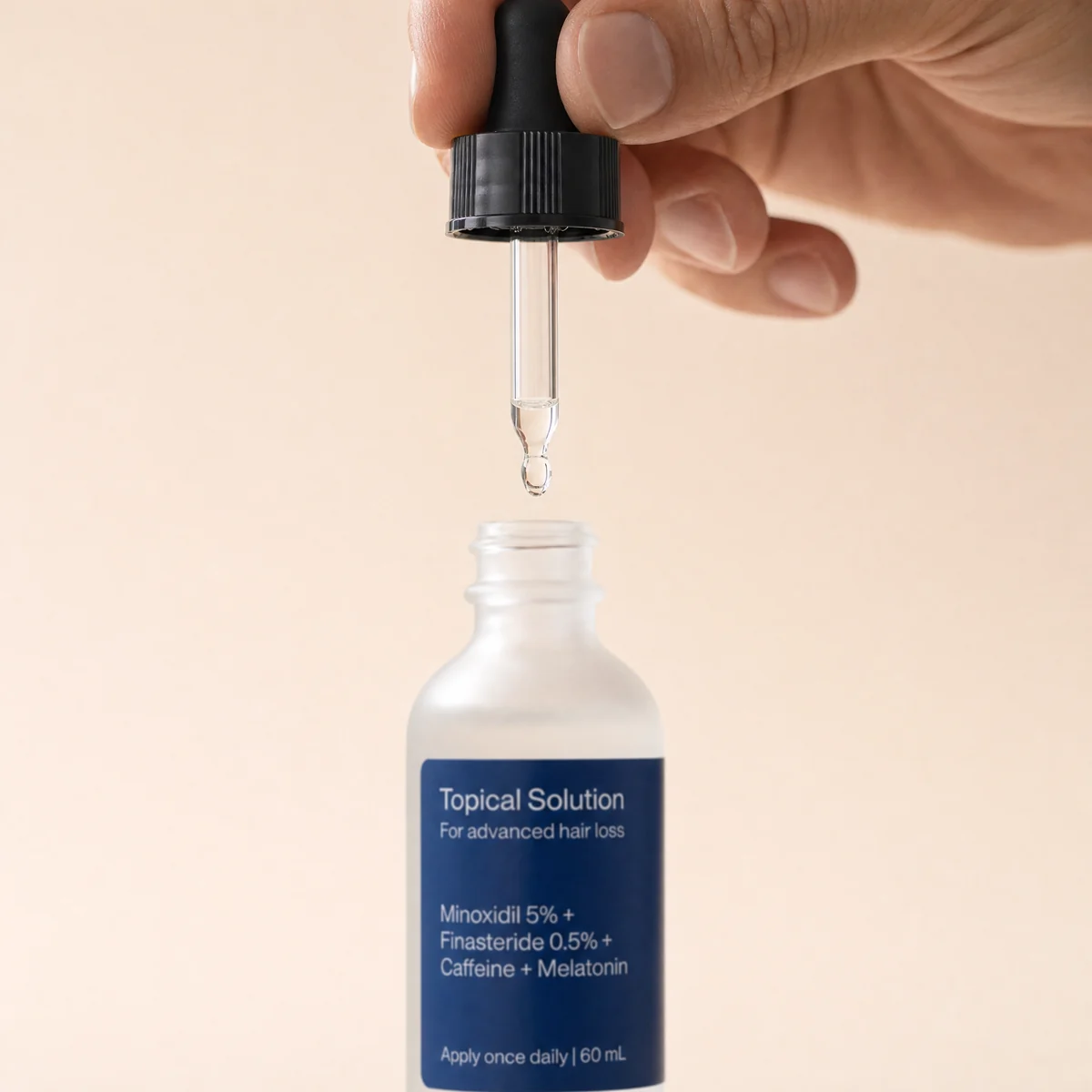 A drop of topical solution forming at the tip of its dropper