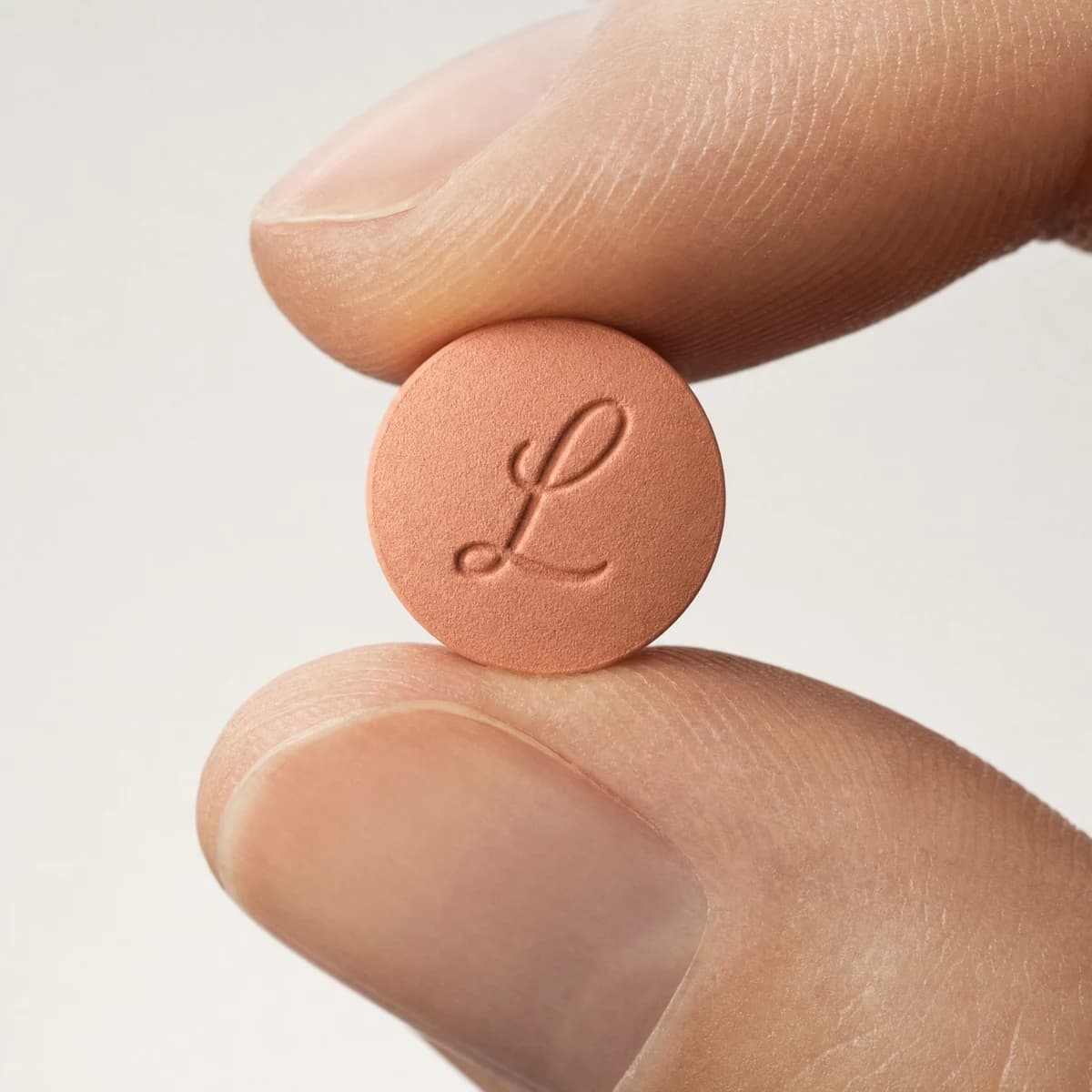 The once daily Foundayo tablet, held between two fingertips